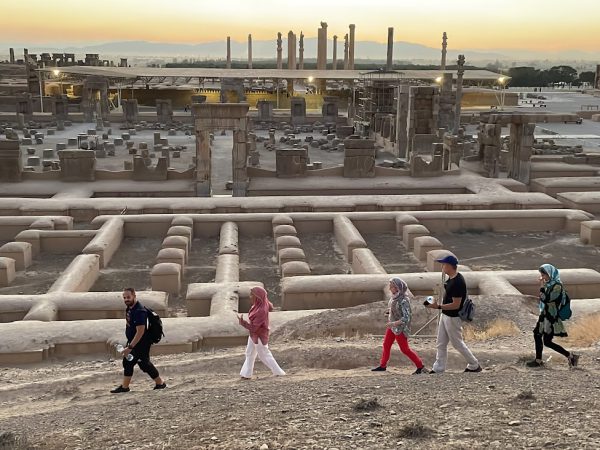 Close-up of tourists viewing detailed stone reliefs of dignitaries at Apadana Palace in Persepolis | Iran’s Travel