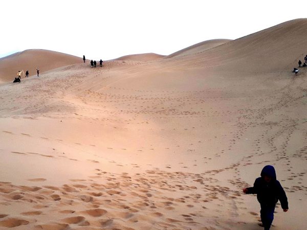 Tourists walking barefoot along the sweeping dunes of Bafgh Desert under a clear sky | Iran&rsquo;s Travel