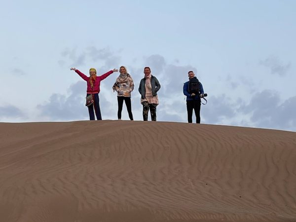Tourists trekking barefoot along high sand dunes in Mesr Desert under a clear blue sky | Iran&rsquo;s Travel