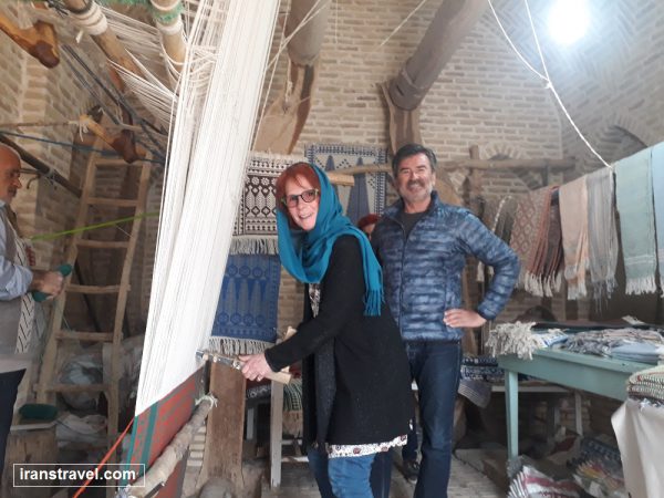 Inside Zeloo Museum in Meybod, Iran, showing traditional looms and colorful handwoven carpets.